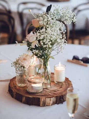 Centerpiece of baby's breath and roses with candles on a wood slice