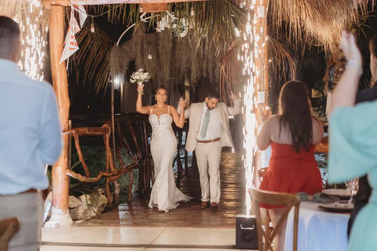 Bride and groom entering the reception under string lights and hanging moss