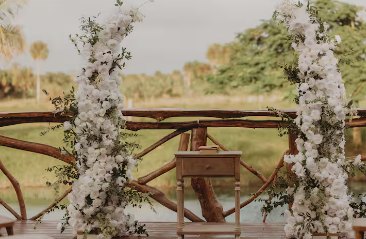 Floral ceremony arch of white blooms on the wooden deck over the lagoon