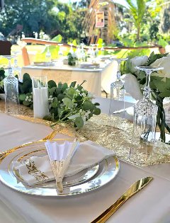 Place setting with charger plate, gold cutlery and folded napkin