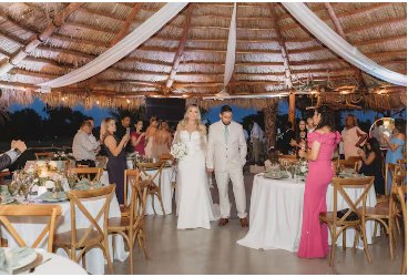 Wedding party gathered at round tables under the covered pavilion roof